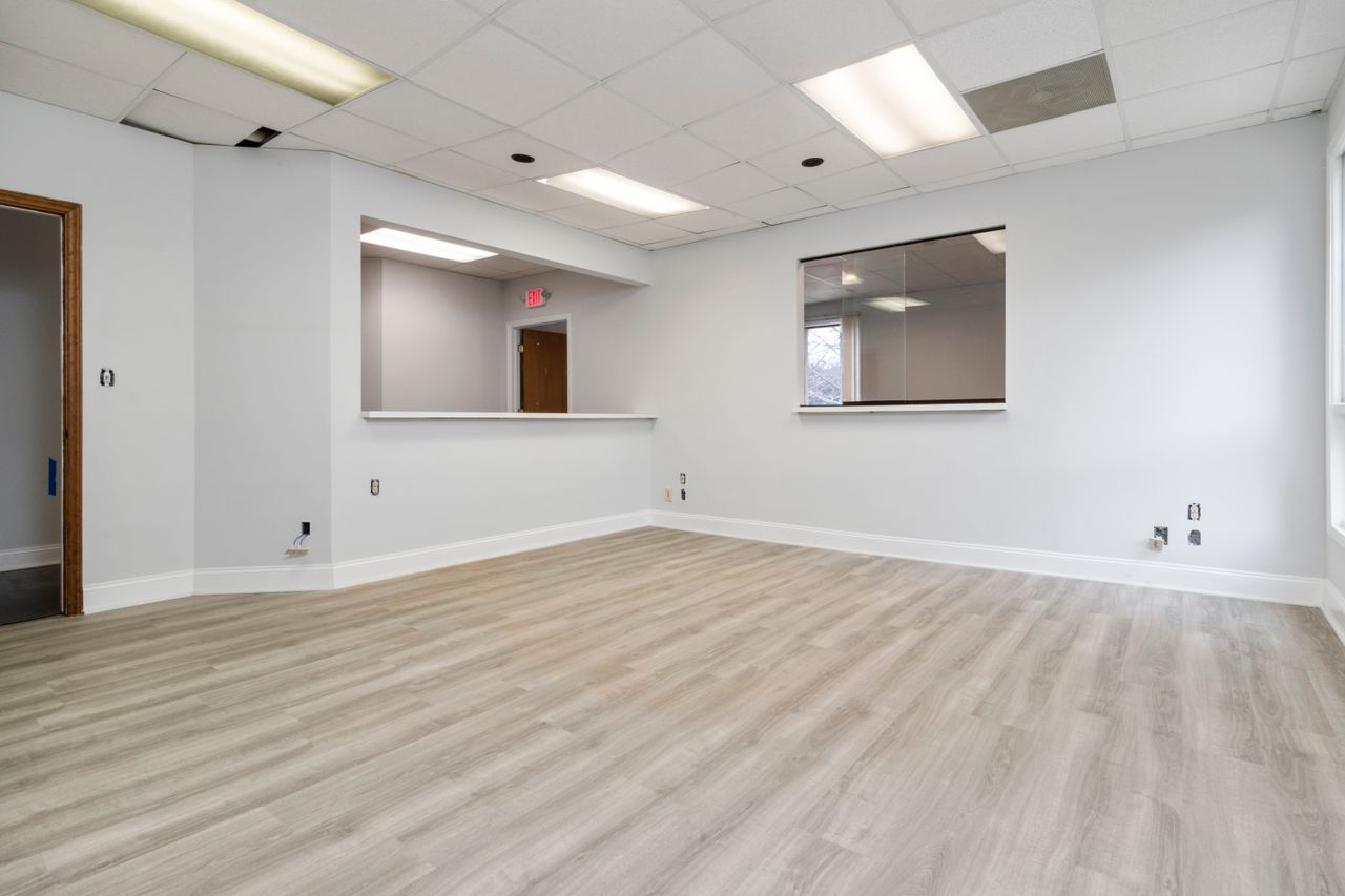 Modern and spacious empty room with wooden flooring and recessed lighting.